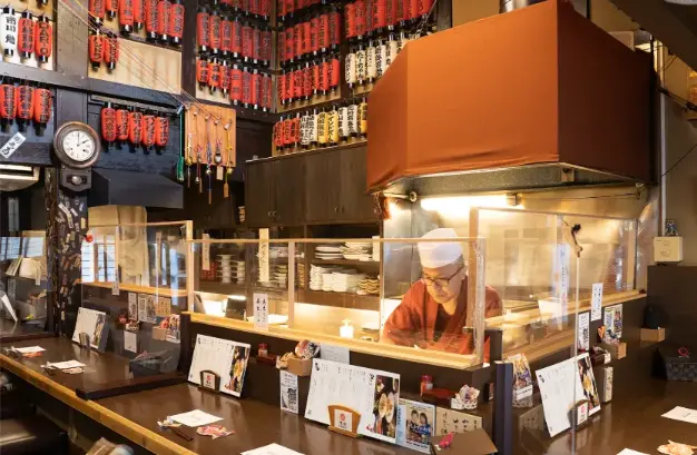 "The cozy interior of a traditional Japanese izakaya, with wooden decor and warm lighting."