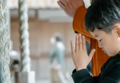 Shrine or Temple in Japan? 7 Key Differences You Need to Know "A parent and child bowing and offering prayers with hands together in front of a saisenbako (offering box) at a Japanese shrine, reflecting a traditional moment of devotion and wish-making."