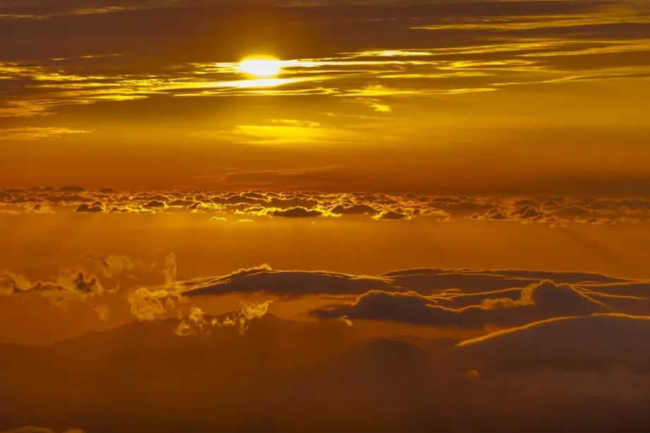 A golden sunset shining above a sea of clouds on Mount Hakusan. Soft rays of light stream through the clouds, creating a warm and breathtaking scene.