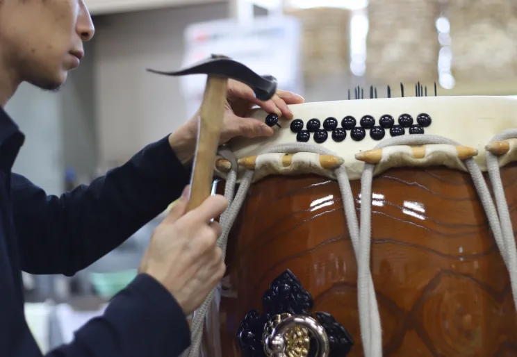 A craftsman carefully assembling a traditional Japanese taiko drum by hand in the Hakusan area.