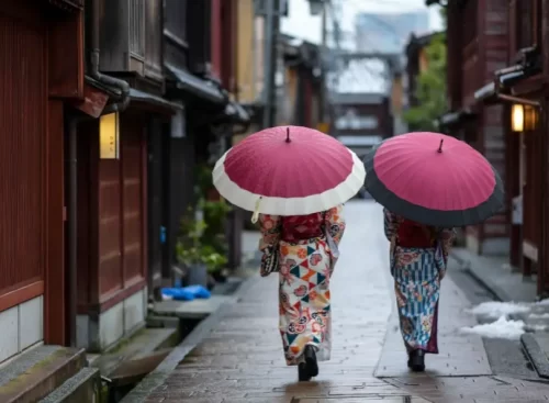 Travelers wearing kimono walk quietly under traditional umbrellas through the historic Higashi Chaya District in Kanazawa.