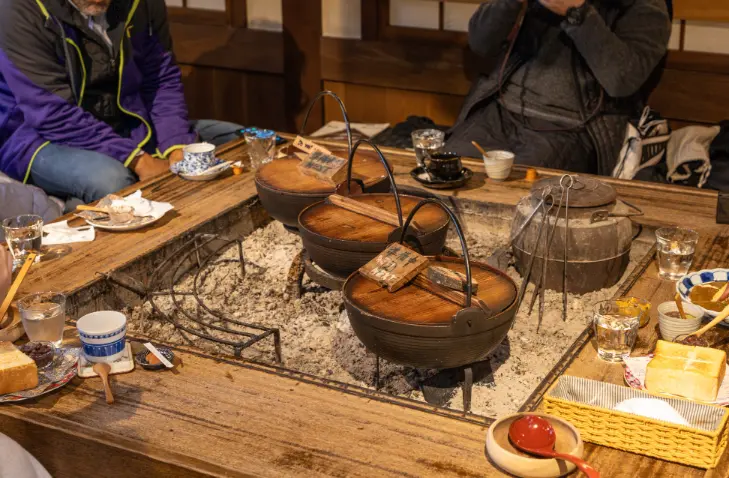 Guests dining together around the irori hearth inside a Gassho-style guesthouse in Shirakawa-go