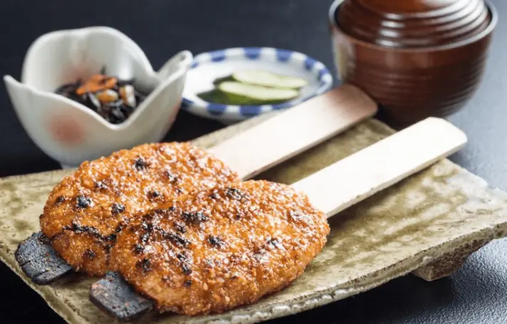 Close-up of Gohei-mochi and skewered grilled river fish served in Shirakawa-go, showcasing local mountain cuisine