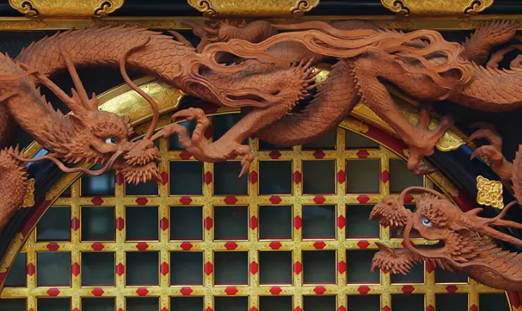 Intricately carved wooden dragons adorning a traditional Japanese temple gate.