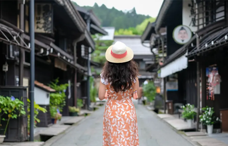 Traveler in a summer dress walking through the traditional old town streets of Takayama, Japan.