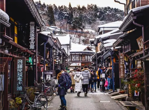 Visitors walking quietly through Takayama’s preserved old-town streets under the soft morning or evening light