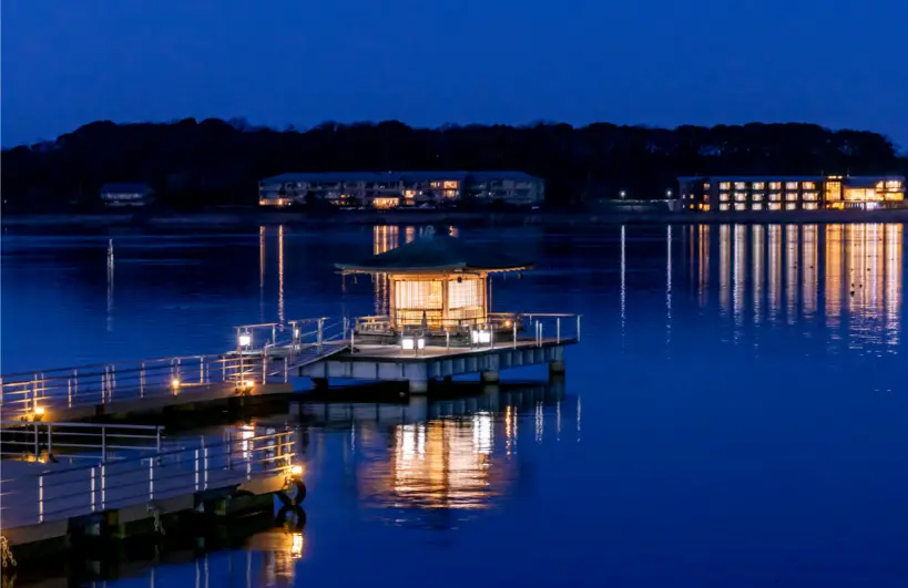 Private tour vehicle driving along scenic lakeside road in Kaga