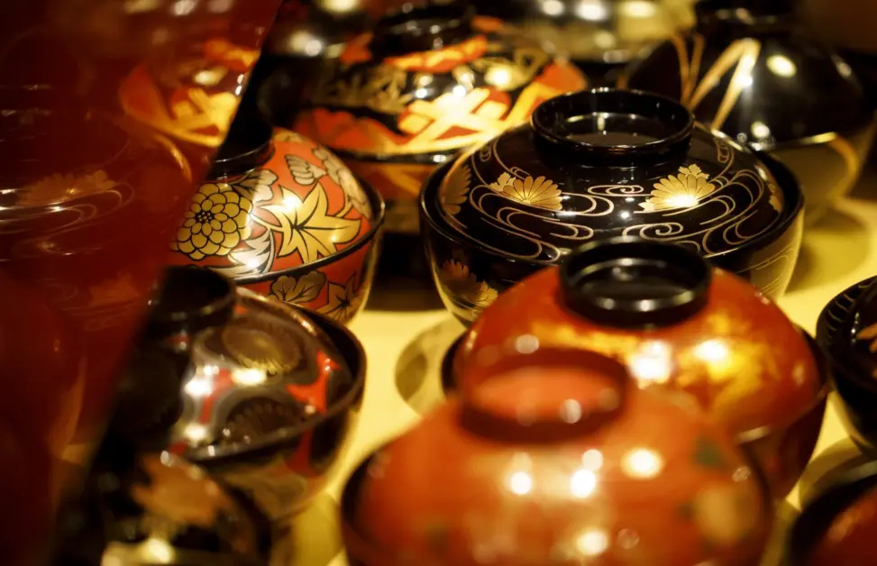 Traditional Wajima lacquerware bowls with elegant gold and red designs on display