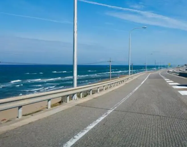 Scenic view of the Noto Satoyama Kaido coastal expressway running alongside the blue sea under a clear sky