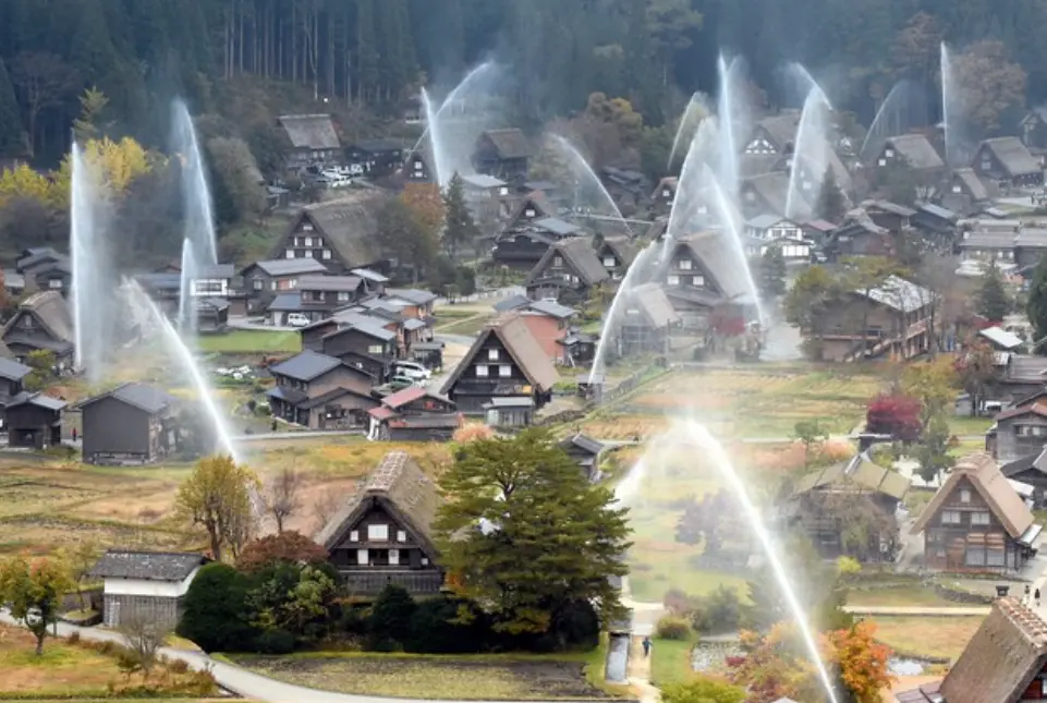 A dramatic display of water cannons spraying over the thatched-roof village of Ogimachi during the annual fire prevention drill.