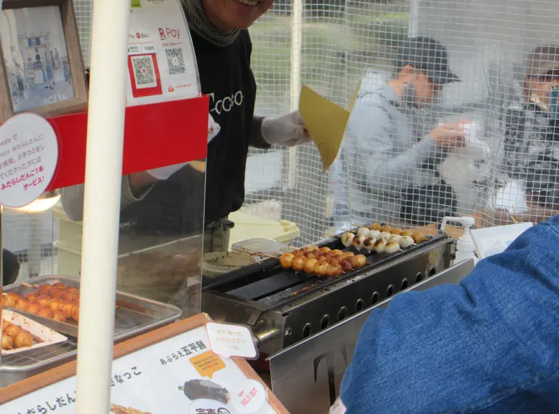 A vendor grilling traditional mitarashi dango skewers at Takayama’s Miyagawa Morning Market.