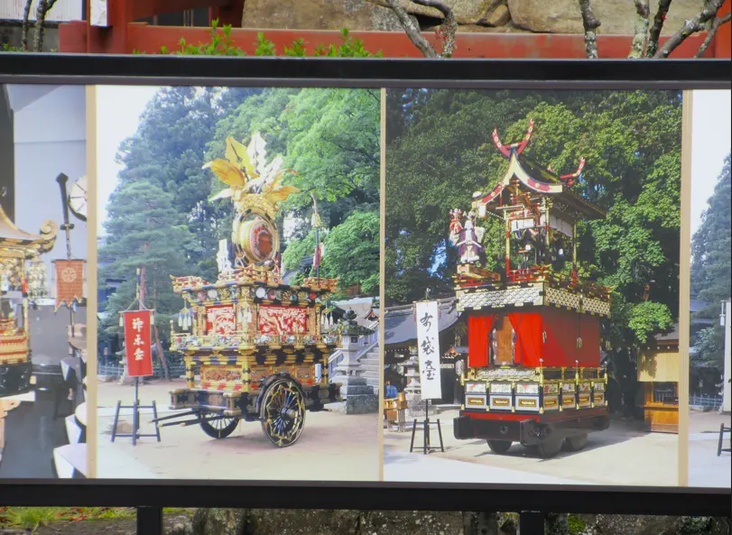 Outdoor display board featuring multiple Takayama Festival floats, showcasing the ornate designs of traditional yatai.