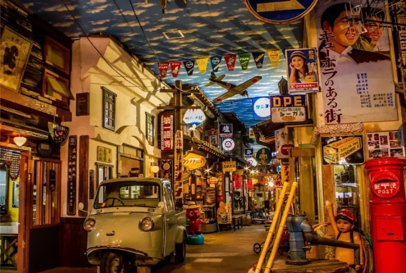 A large-scale Showa-era street scene inside the Takayama Showa Museum, featuring a vintage three-wheeled truck, old signs, and nostalgic décor.