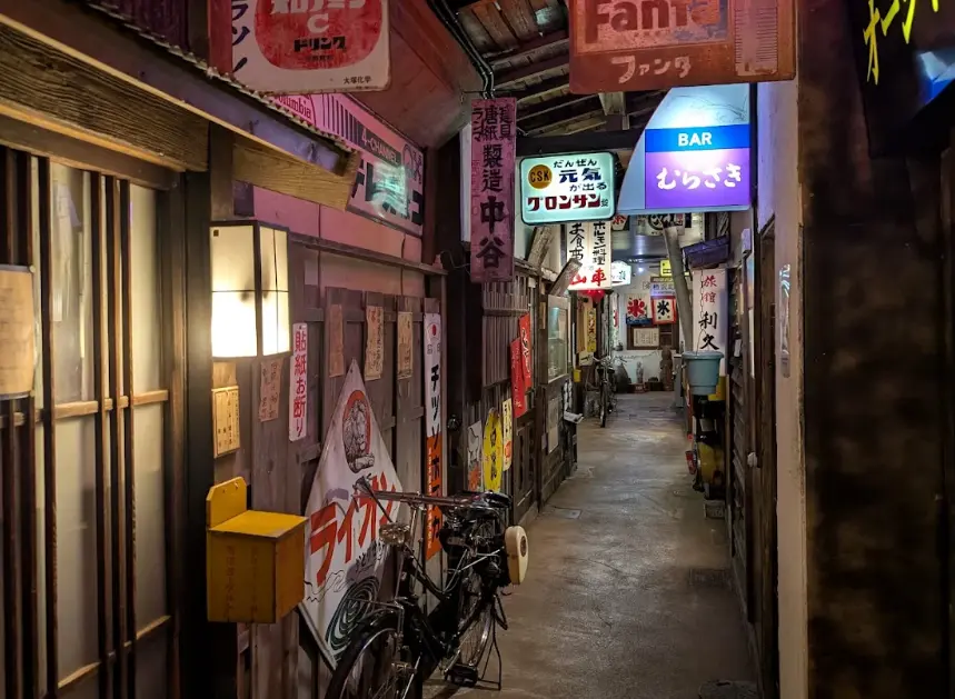 Narrow Showa-era alley recreated inside the Takayama Showa Museum, lined with retro signs, lanterns, and an old bicycle.