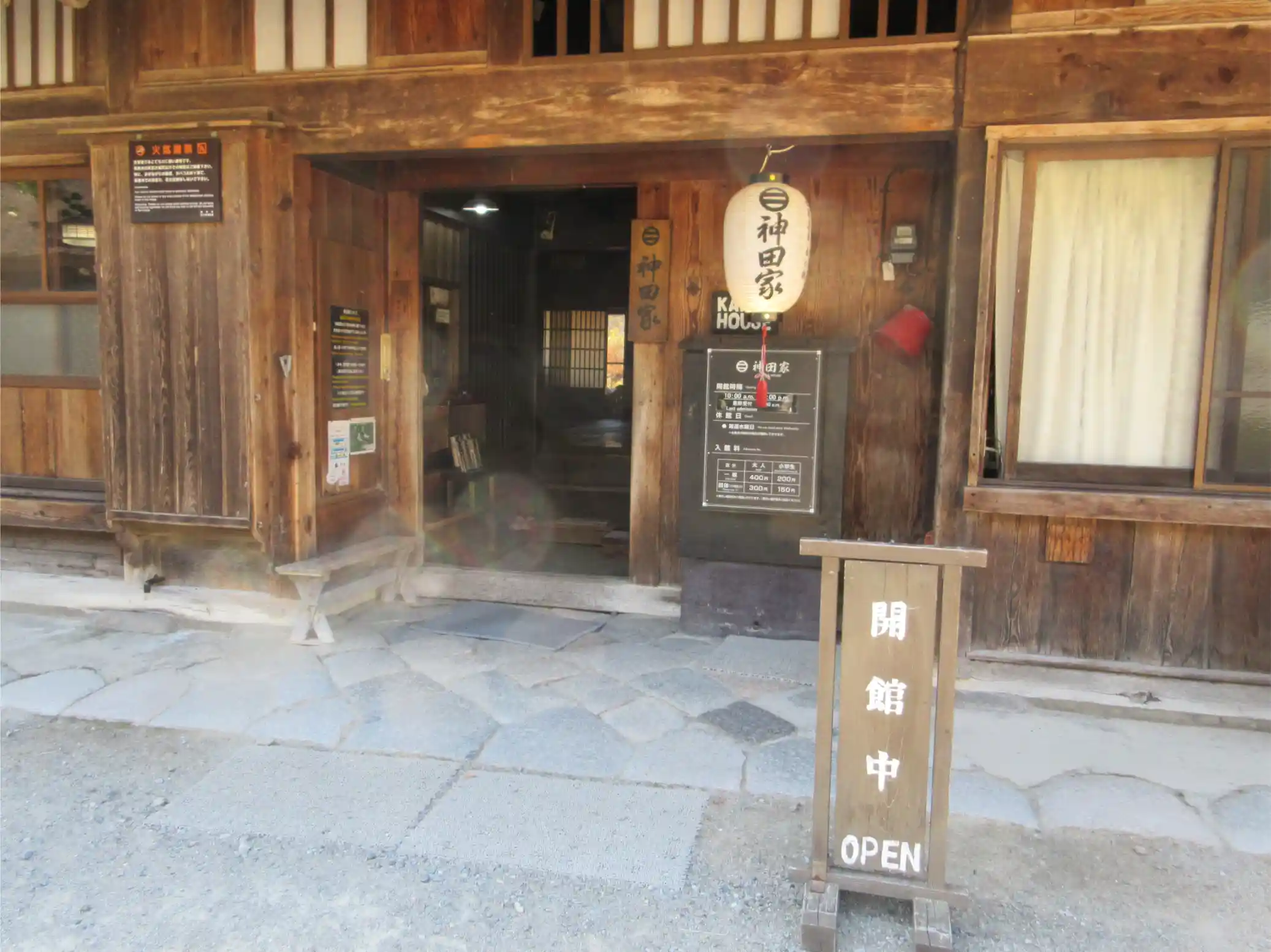 The main entrance of Kanda House in Shirakawa-go, a traditional gasshō-zukuri home, with an open sign inviting visitors inside.