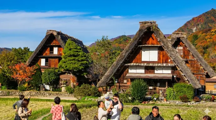 Scenic view of traditional Gassho-zukuri farmhouses in Shirakawa-go with mountains in the background.