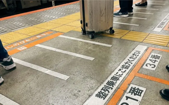 Marked boarding lines on a Japanese train platform showing where passengers queue in an orderly manner.