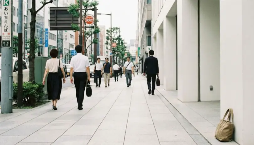 A bag placed beside a city sidewalk in Japan, left undisturbed in a calm urban setting.