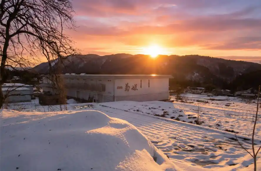 Snow-covered fields in the Hakusan area with mountains in the background, illuminated by the setting sun.
