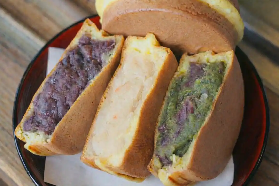 Slices of Japanese filled cake with red bean and green paste, served on a plate as a local sweet in the Hakusan area.
