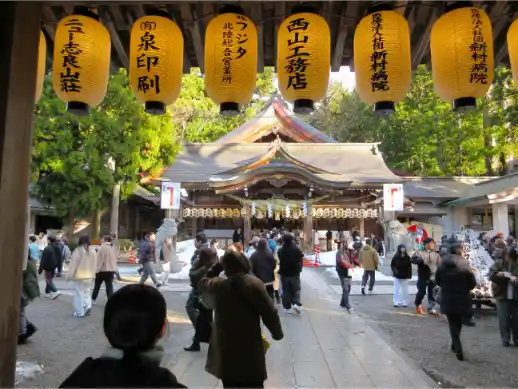 People gathering at a shrine in the Hakusan area, seen through hanging lanterns with forested surroundings.