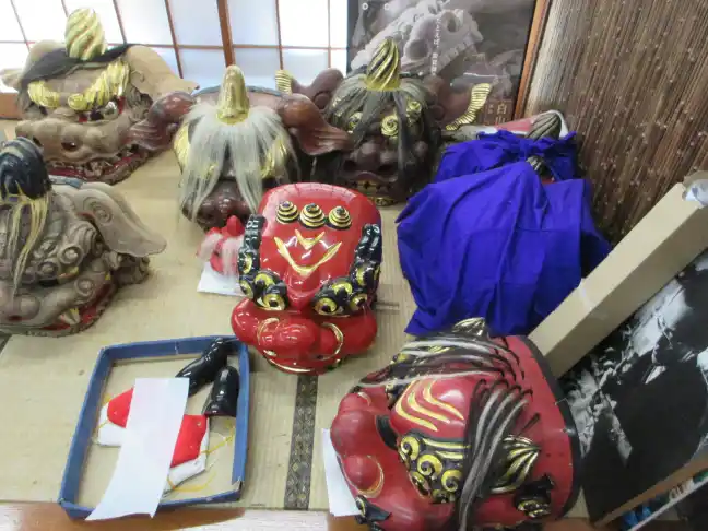Assorted wooden and lacquered Shishi lion dance masks representing different local festival styles arranged on tatami