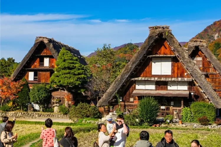 Scenic view of traditional Gassho-zukuri farmhouses in Shirakawa-go with mountains in the background.